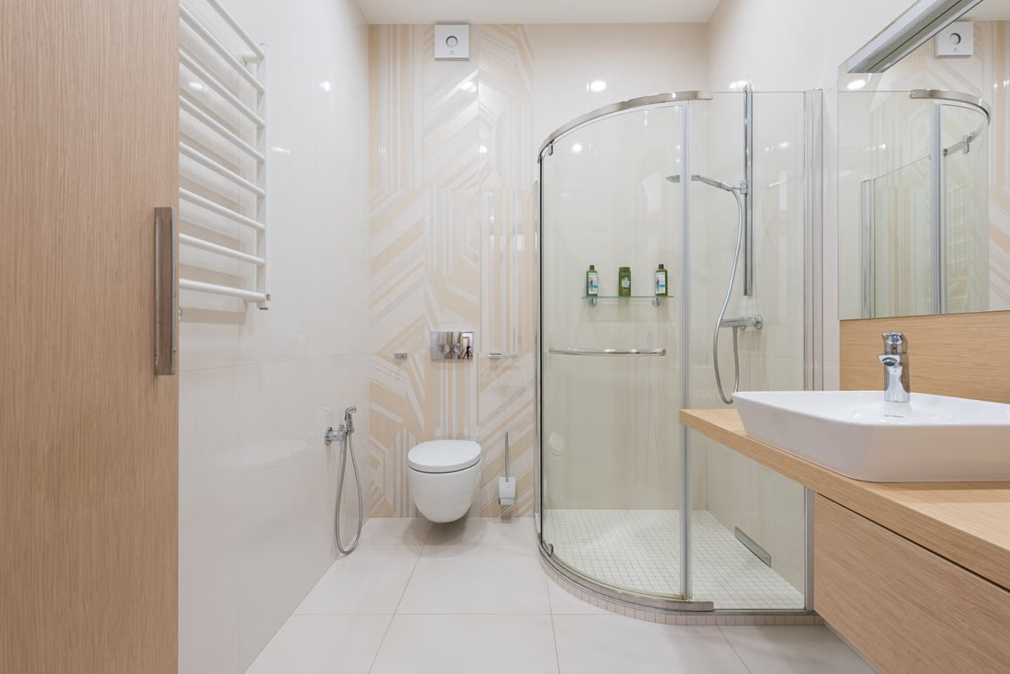 Baño reformado con ducha angular de cristal y mueble de madera