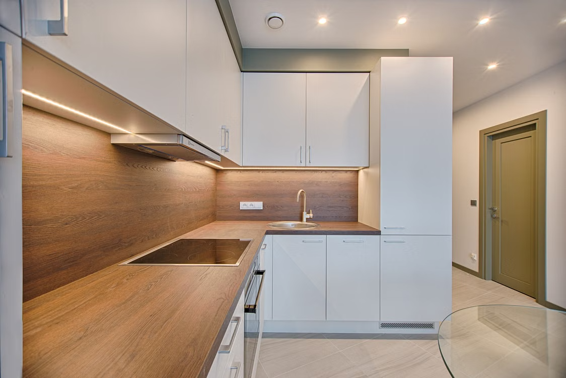 Cocina reformada con muebles blancos, encimera de madera y grifo negro