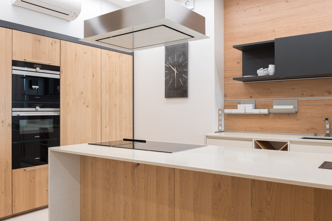 Cocina reformada con isla de encimera clara, muebles de madera y placa de inducción